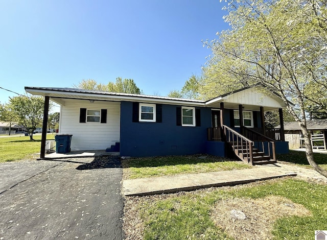 single story home featuring a porch, aphalt driveway, a front yard, and metal roof