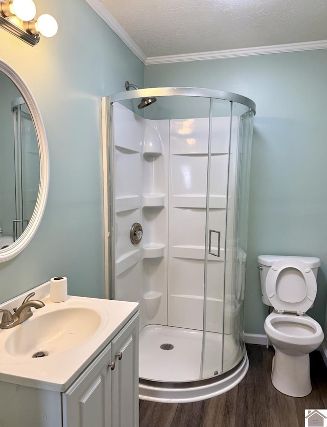 bathroom featuring a shower stall, wood finished floors, toilet, vanity, and crown molding