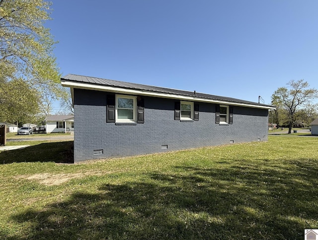 view of home's exterior with brick siding, crawl space, a yard, and metal roof