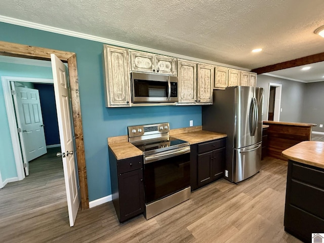 kitchen featuring baseboards, appliances with stainless steel finishes, and light wood finished floors