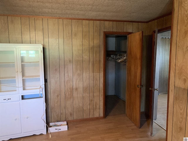 1368 Pritchard Rd, Wingo, KY 42088 - unfurnished bedroom with a spacious closet, wood walls, ornamental molding, a closet, and light wood-style flooring