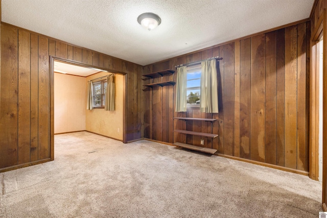 carpeted empty room with a textured ceiling and wooden walls