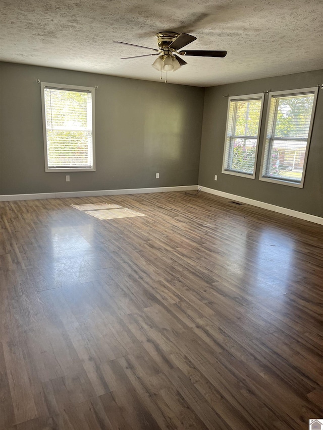 spare room featuring dark wood-type flooring, a healthy amount of sunlight, and a ceiling fan