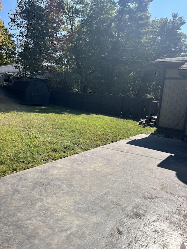 view of yard with an outdoor structure, a storage unit, a fenced backyard, and a patio