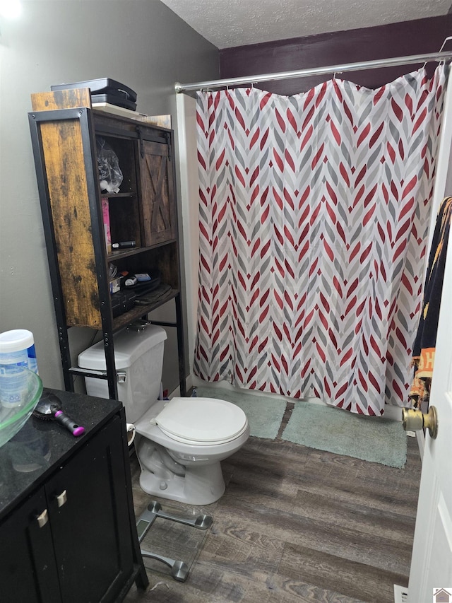 full bath with wood finished floors, curtained shower, a textured ceiling, and toilet