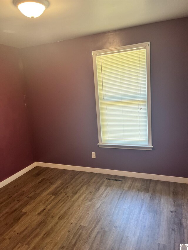 empty room featuring dark wood finished floors, baseboards, and visible vents