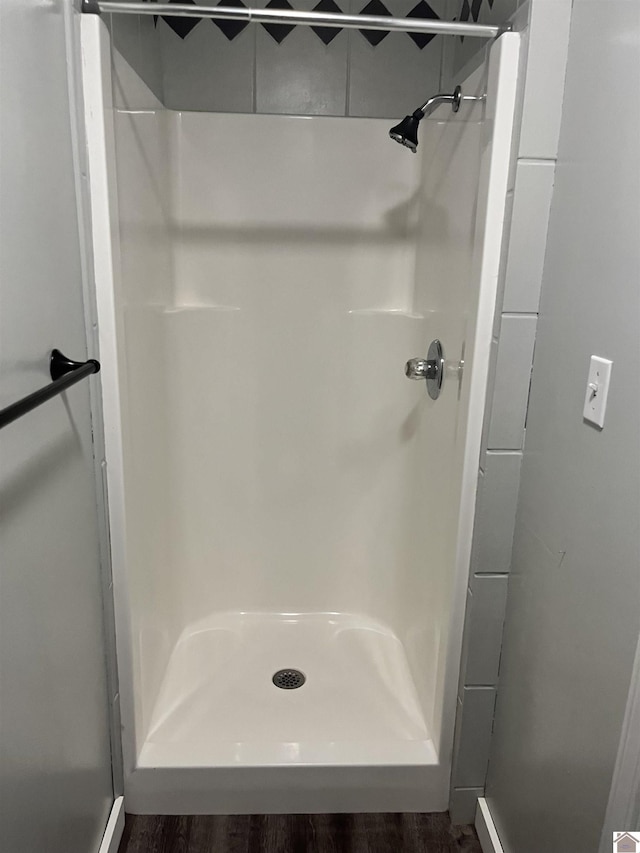 full bathroom featuring wood finished floors and a stall shower