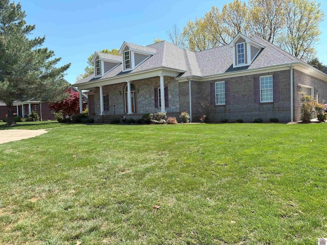 cape cod home with a front lawn, roof with shingles, covered porch, and stone siding