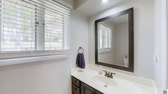 bathroom with toilet, vanity, and plenty of natural light