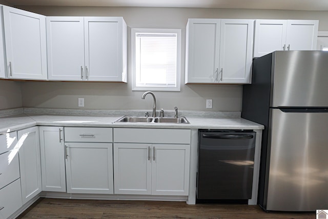 kitchen with freestanding refrigerator, light countertops, white cabinets, a sink, and dishwashing machine