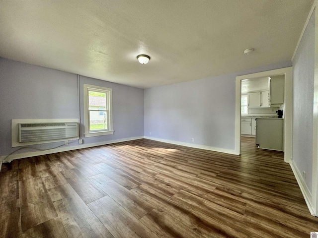 interior space with baseboards, a textured ceiling, dark wood-type flooring, and an AC wall unit