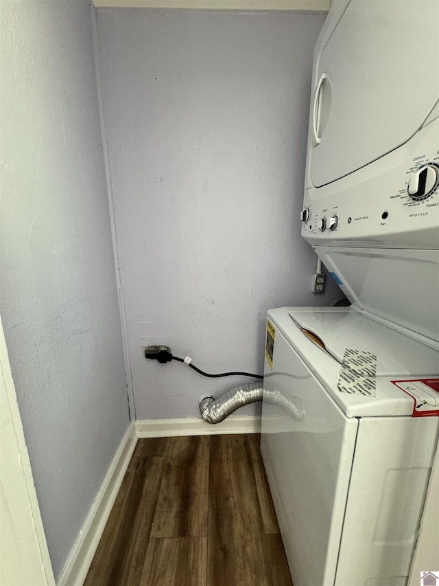 washroom with laundry area, stacked washing maching and dryer, wood finished floors, and baseboards
