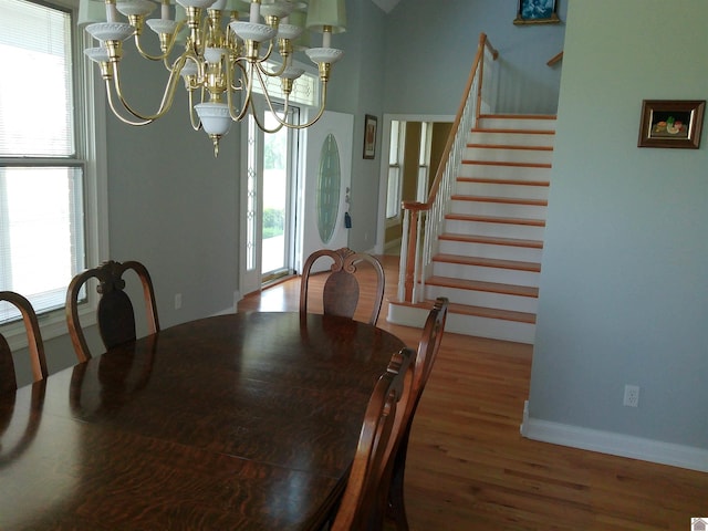 dining room with baseboards, stairway, wood finished floors, and a notable chandelier