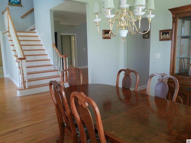 dining area with baseboards, wood finished floors, an inviting chandelier, and stairs