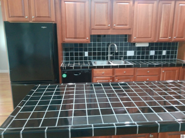 kitchen with decorative backsplash, a sink, freestanding refrigerator, dishwashing machine, and tile countertops