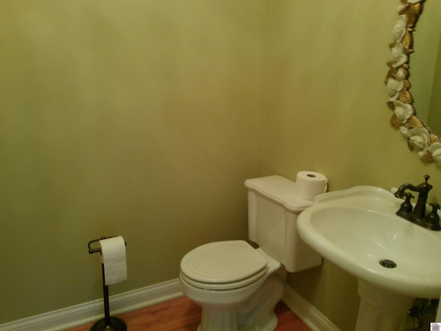 bathroom with a sink, wood finished floors, toilet, and baseboards