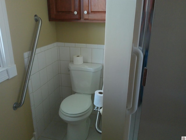 bathroom with toilet, tile walls, and wainscoting
