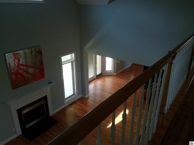 unfurnished living room featuring baseboards, wood finished floors, a high ceiling, and a fireplace with flush hearth