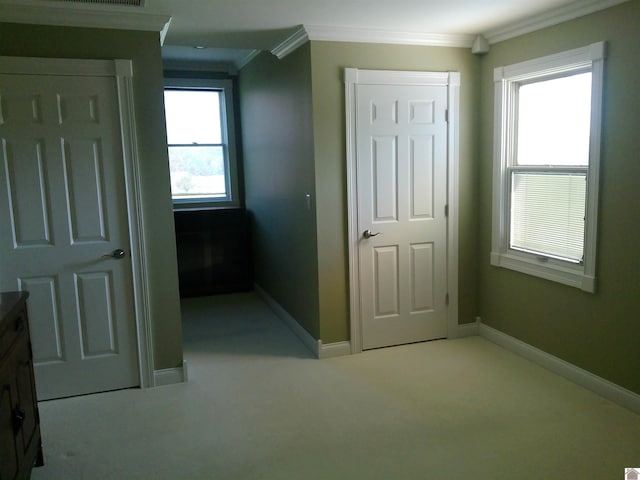 unfurnished bedroom with baseboards, ornamental molding, multiple windows, and light colored carpet