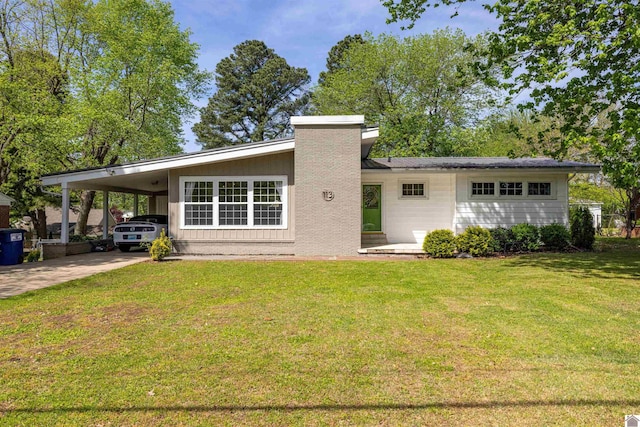 back of property featuring a carport, concrete driveway, a yard, and a chimney