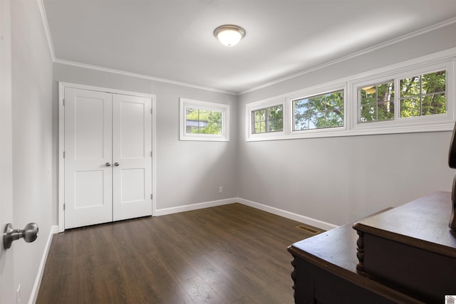 interior space with dark wood-type flooring, visible vents, ornamental molding, and baseboards