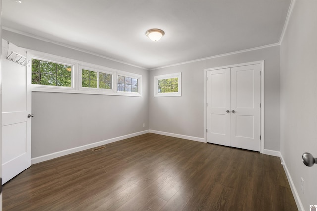 unfurnished bedroom featuring visible vents, ornamental molding, dark wood finished floors, and baseboards