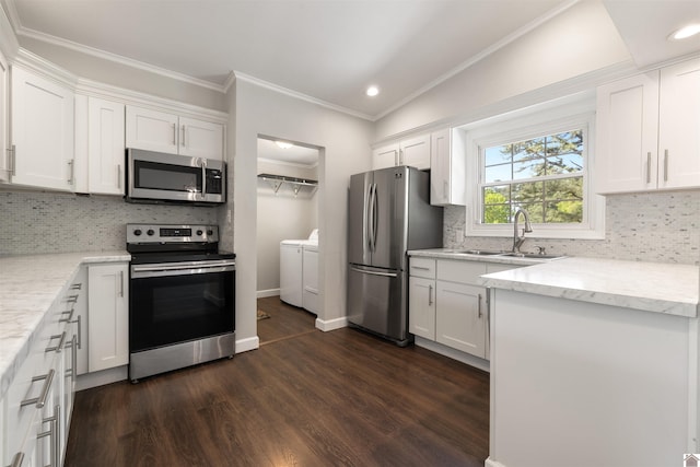 kitchen with white cabinets, a sink, stainless steel appliances, washer and dryer, and dark wood-type flooring