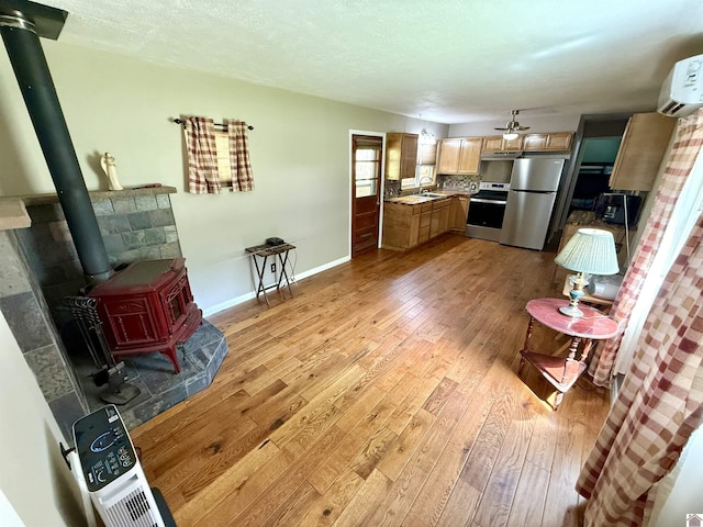 124 Miller Ln, Gilbertsville, KY 42044 - interior space featuring a wood stove, ceiling fan, baseboards, and light wood-style floors