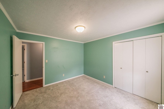 unfurnished bedroom with a closet, crown molding, baseboards, and carpet floors
