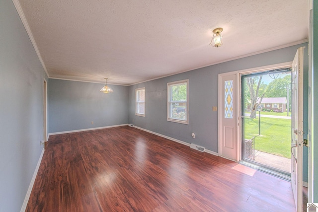 interior space with wood finished floors, visible vents, ornamental molding, and a textured ceiling