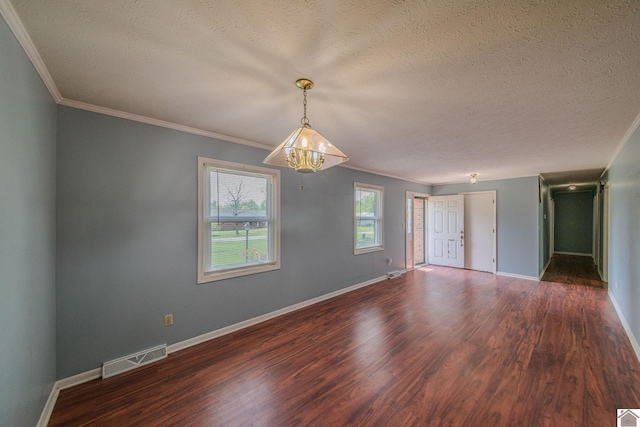 unfurnished room featuring ornamental molding, a textured ceiling, wood finished floors, and baseboards