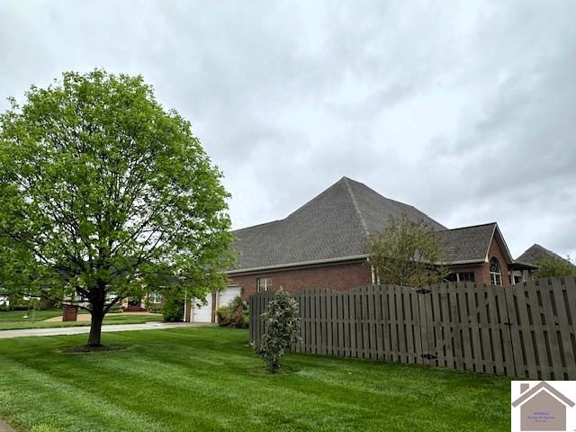 57 Rippling Creek Dr, Murray, KY 42071 - view of property exterior with a lawn, a garage, brick siding, and fence