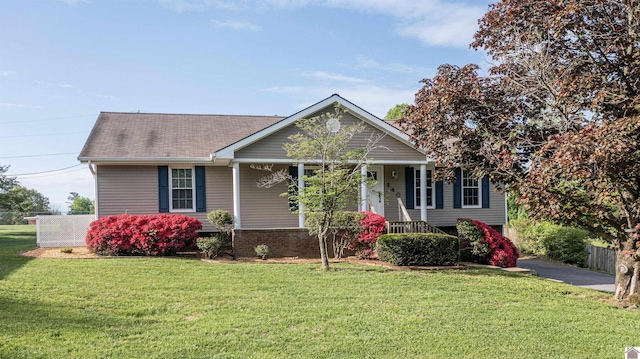 view of front of house with a porch, fence, a front yard, and a shingled roof