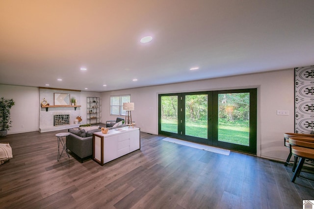 living room featuring a fireplace with raised hearth, recessed lighting, baseboards, and dark wood finished floors
