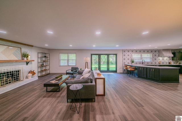 living area with wood finished floors, a tiled fireplace, and recessed lighting