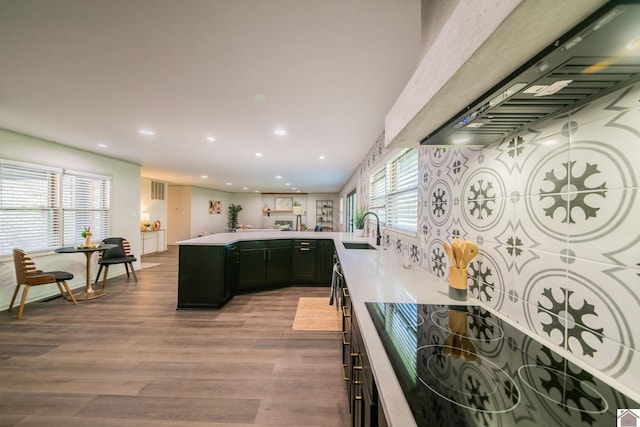 kitchen featuring recessed lighting, a sink, black electric stovetop, wall chimney exhaust hood, and wood finished floors