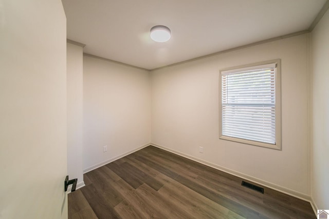 spare room with visible vents, crown molding, dark wood finished floors, and baseboards