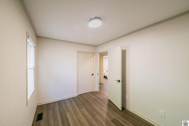 empty room featuring plenty of natural light, dark wood finished floors, and baseboards