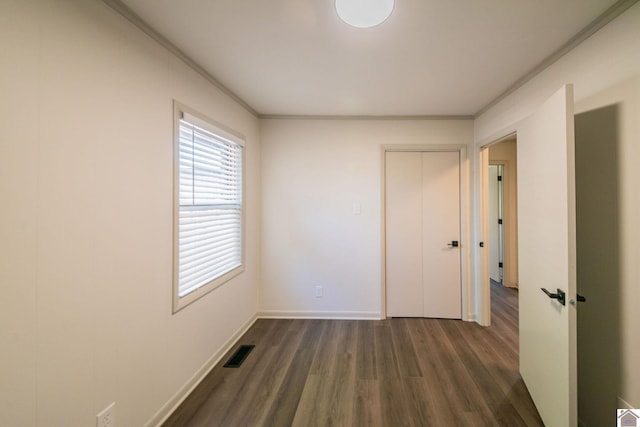 spare room featuring crown molding, visible vents, baseboards, and dark wood-type flooring