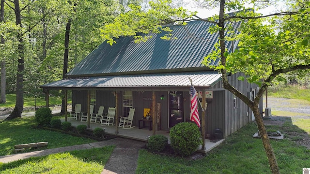 view of front facade featuring covered porch, metal roof, and a front lawn