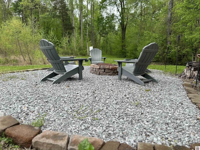view of yard featuring a wooded view and an outdoor fire pit