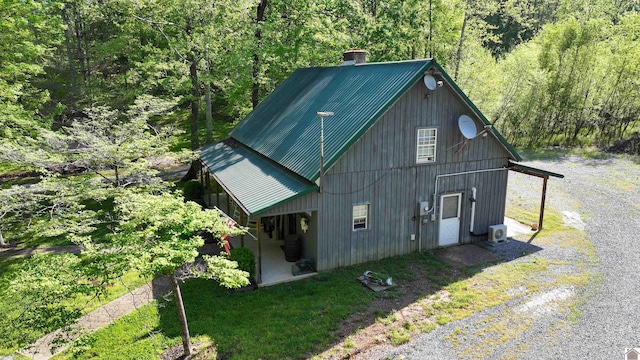 exterior space featuring a chimney, metal roof, and a view of trees