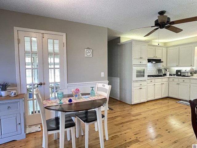 11189 E State Route 94, Murray, KY 42071 - dining room featuring a textured ceiling, light wood-type flooring, french doors, a ceiling fan, and wainscoting