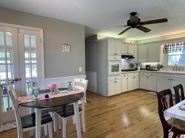11189 E State Route 94, Murray, KY 42071 - kitchen with white oven, under cabinet range hood, black gas cooktop, a sink, and a ceiling fan