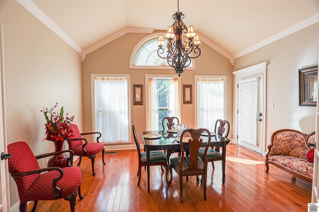 dining space with baseboards, hardwood / wood-style flooring, a notable chandelier, and vaulted ceiling