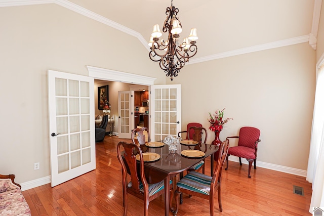 dining space featuring baseboards, light wood-type flooring, a notable chandelier, and french doors