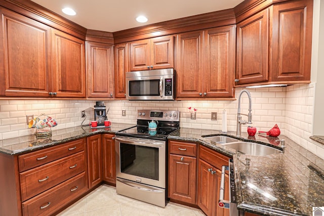 kitchen featuring dark stone counters, a sink, light tile patterned floors, and stainless steel appliances