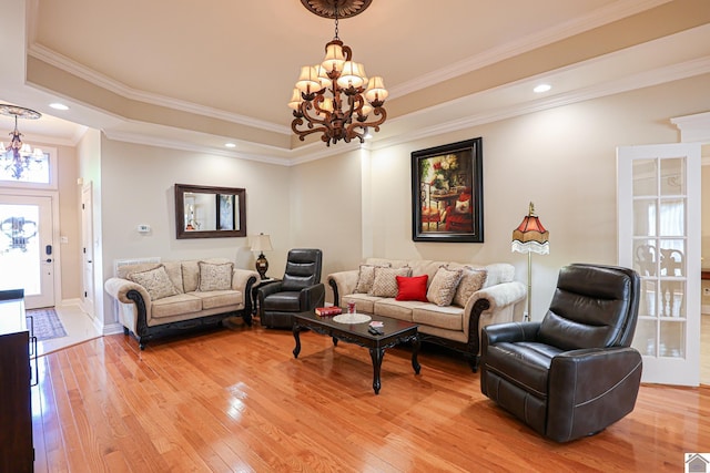 living area with crown molding, a chandelier, light wood-style floors, a tray ceiling, and baseboards