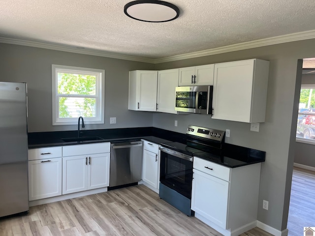 kitchen featuring a textured ceiling, a sink, stainless steel appliances, and light wood-type flooring