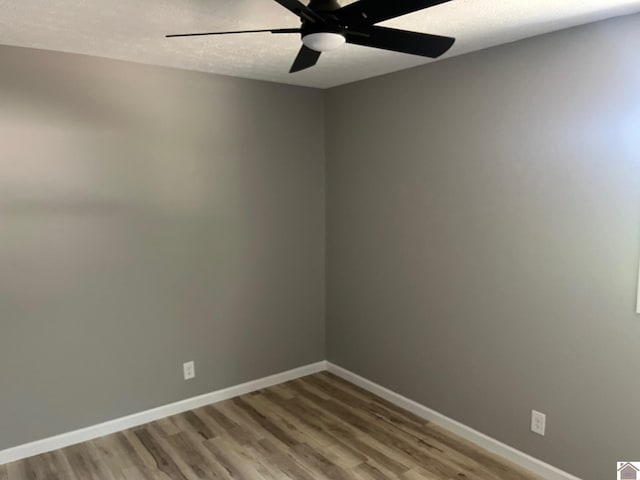 spare room with wood finished floors, ceiling fan, a textured ceiling, and baseboards